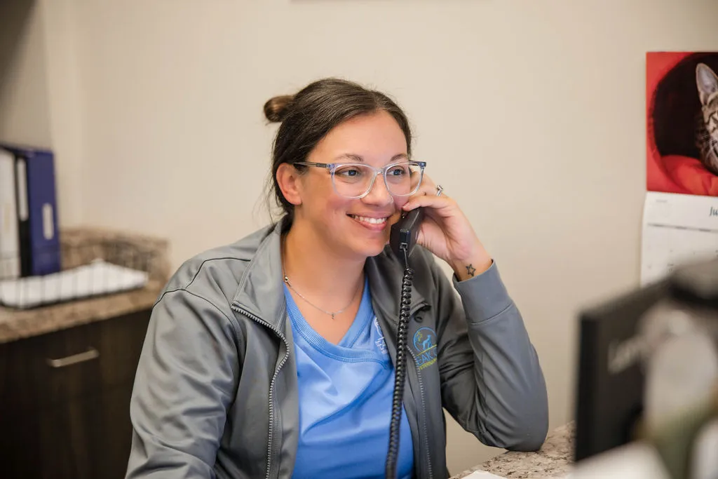 Smiling Peak City Veterinary Hospital receptionist talking with a client on the phone